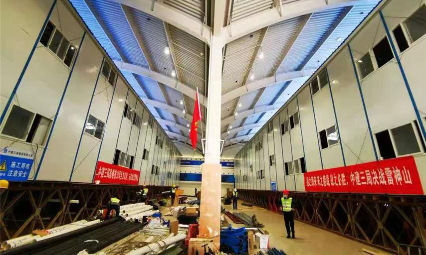 截至1月30日中午12時，雷神山醫院項目總體建設進度完成40％。隔離病房區場地平整、溝槽開挖、溝槽管線預埋、非溝槽區PE膜施工全部完成，溝槽回填已完成90％，條形基礎施工完成60％；集裝箱總計進場1518間，場外改裝完成約300套，現場已完成吊裝30間。醫護人員生活區A1－A7棟完成板房框架梁柱、樓面板、墻面板、屋面板等結構施工的70％。圖為醫護住宿區板房結構施工現場。