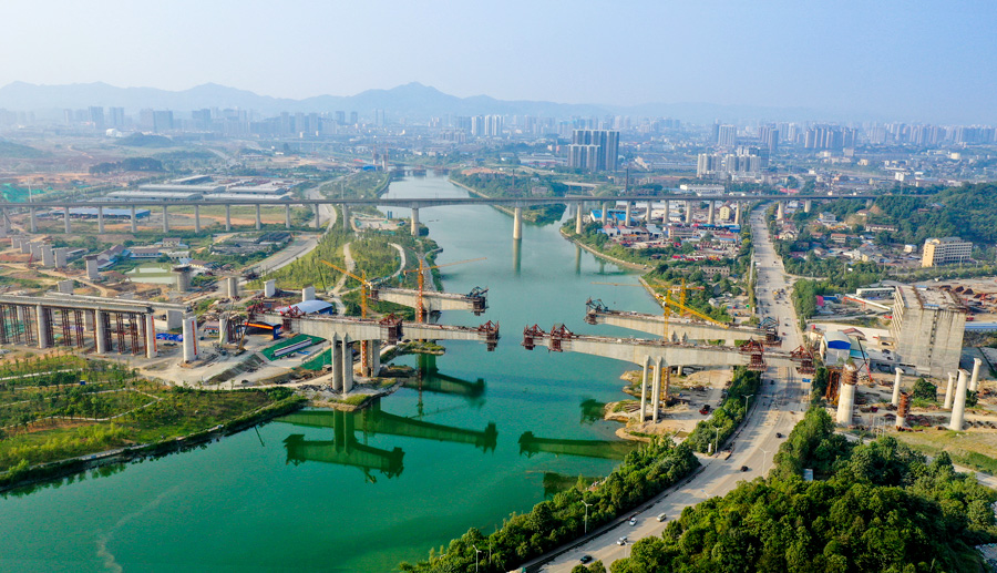 渝懷二線鐵路是國家中長期鐵路網規劃和國家鐵路“十二五”發展規劃的重要建設項目，承擔著武陵山區區域發展與扶貧攻堅的重任。由中國鐵建所屬中鐵二十五局承建的舞水灣特大橋是渝懷二線鐵路重難點工程，包含三座主跨168米的連續梁并列跨過舞水河，環水保要求高。項目部成立環水保專項工作組，通過掛籃兜底隔離防護、廢水三級沉淀處理等措施，用綠色施工呵護懷化市母親河及沿河風光帶。圖為施工中的舞水灣特大橋。