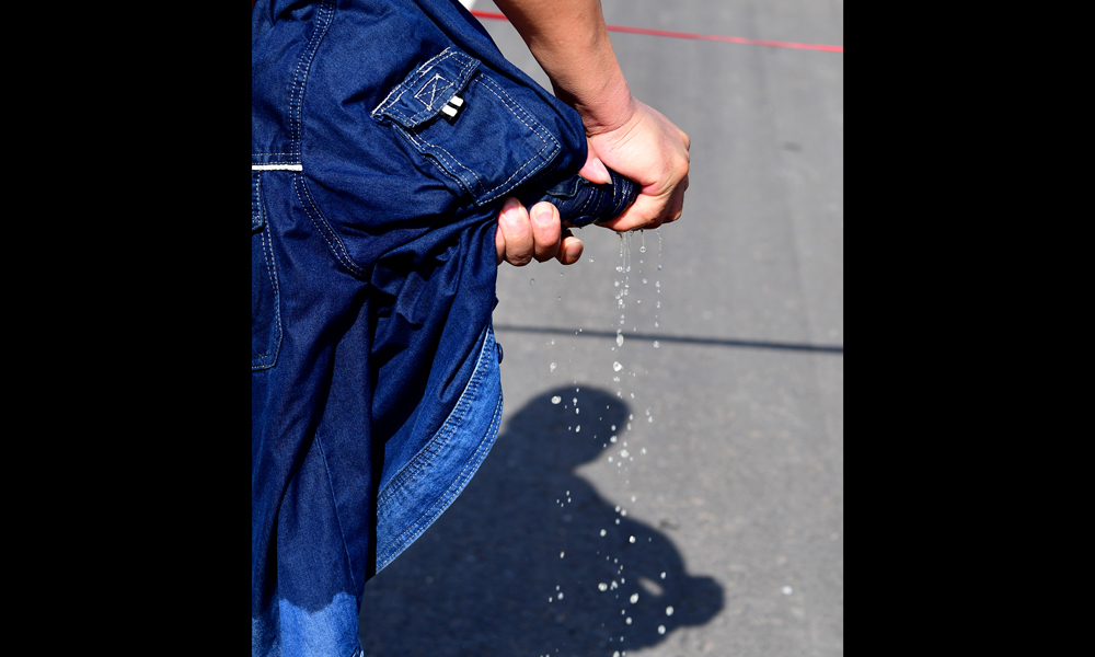 圖為7月30日，在河南省新安縣正村鎮上坡村，尤寧結束帶電作業后，所穿的工作服中擰出了水。（新華社記者 馮大鵬 攝）