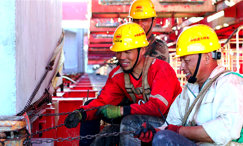 圖為工作人員調整最后一片鐵路節(jié)段梁。