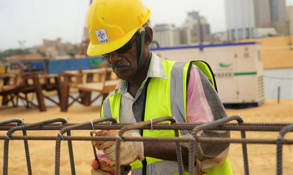 隨著科倫坡港口城填海造地工程完工以及市政設施建設陸續(xù)啟動，這座由中國和斯里蘭卡在“一帶一路”倡議下聯合開發(fā)的南亞新城邁入發(fā)展新階段。目前中斯正在攜手推動港口城的招商工作。根據雙方愿景，港口城內將推行一系列惠商措施以吸引全球投資者，為斯里蘭卡打造開放經濟新高地。圖為7月22日，一名當地工人在斯里蘭卡科倫坡港口城景觀水道區(qū)域為運河護岸鋼筋籠綁鋼筋。（新華社記者 唐璐 攝）