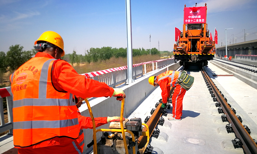 京雄城際鐵路建設工程是國家重點建設項目，是連接北京市區、北京新機場和雄安新區的重要軌道交通線。京雄城際鐵路正線全線北起李營站，南至雄安站，經由大興、固安、霸州、雄安管內。全線鋪軌總長度214公里，道岔鋪設70組，由年鋪軌作業能力千公里以上的中鐵十二局集團獨家承擔。圖為工作人員緊固扣件。