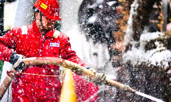 2月14日，正在拖航作業(yè)的“海洋石油923”鉆井平臺迎來降雪。為保障作業(yè)安全平穩(wěn)進(jìn)行，現(xiàn)場工作人員頂風(fēng)冒雪堅守崗位。圖為平臺高級隊長劉海鵬在零下12℃的氣溫下完成該鉆井平臺樁靴及樁腿的淤泥清理工作。