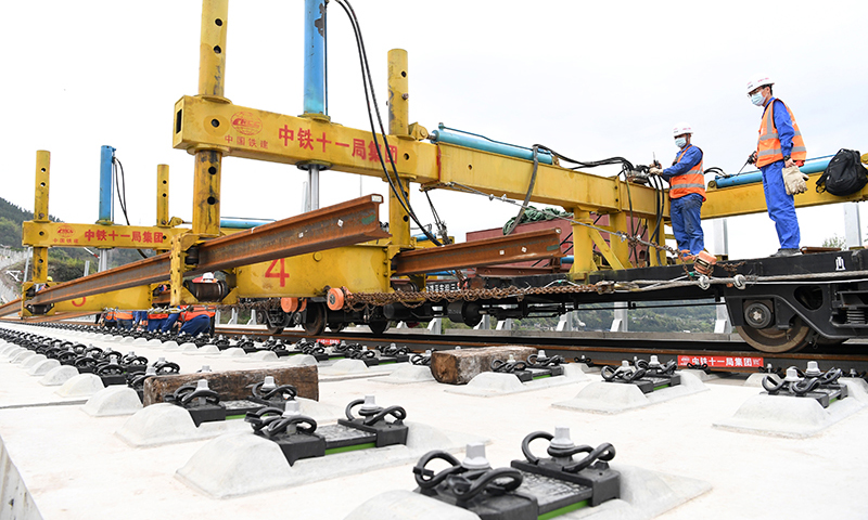 據(jù)了解，這次鄭萬高鐵重慶段鋪軌，首次運(yùn)用了BLCP500型本鄰兩線長軌鋪設(shè)機(jī)組，在第一條線路鋪設(shè)完成、不需要中轉(zhuǎn)的情況下，對鄰線進(jìn)行長軌鋪設(shè)，省去了換線鋪軌牽引車折返時(shí)間，減少了調(diào)車作業(yè)的次數(shù)，鋪軌準(zhǔn)備時(shí)間減少約50%，大幅提升了鋪軌作業(yè)效率。圖為3月17日，BLCP500型本鄰兩線長軌鋪設(shè)機(jī)組進(jìn)行機(jī)械化跨線鋪軌作業(yè)。（新華社記者 唐奕 攝）