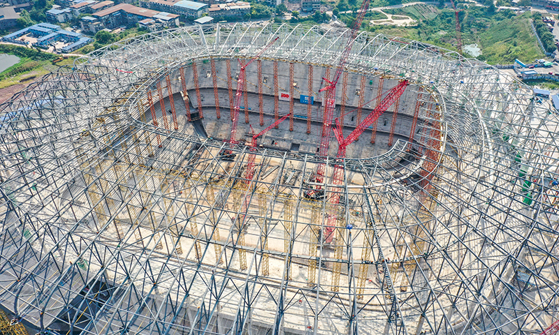 近日，重慶氣溫持續走高，最高氣溫超過40攝氏度。為確保施工進度如期完成，中建八局重慶龍興足球場項目部通過調整施工時間、準備避暑藥品飲料、搭建休息涼亭等方式，合理管控施工進度。目前已完成鋼屋蓋施工進度的90%，鋼結構施工進入收尾階段，室內正進行二次結構施工。圖為重慶龍興足球場屋蓋鋼結構施工現場（無人機照片）。新華社發 羅俊 攝