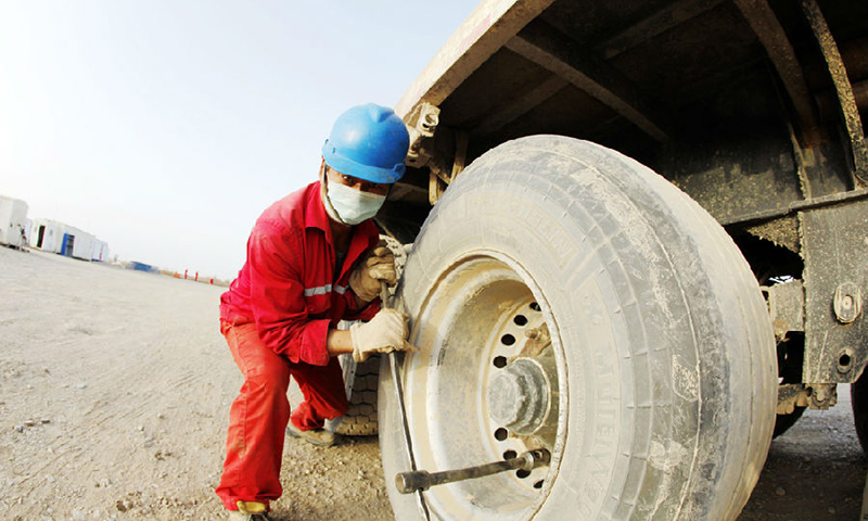 伴隨著鉆機的轟鳴，位于塔里木油田柯克亞氣田的柯7K-H1井順利開鉆，比計劃提前4天拉開了油田春季生產的序幕。這口井動遷周期僅用11天，打破了油田500公里以上的長途井動遷紀錄。圖為搬遷工人正在維修車輪。