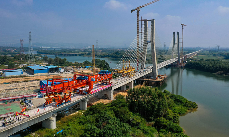 10月25日，中鐵五局承建的廣汕鐵路鋪架施工最后一孔900噸箱梁成功架設(shè)在廣州增江特大橋橋墩上，標志著全線箱梁架設(shè)完成。圖為施工人員操作架橋機將最后一孔900噸箱梁成功架設(shè)在增江特大橋橋墩上（無人機照片）。新華社記者 劉大偉 攝