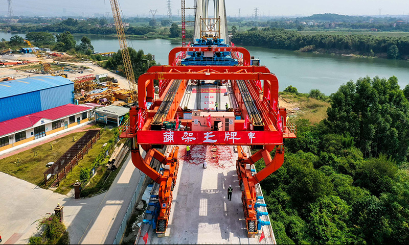 10月25日，施工人員操作架橋機將最后一孔900噸箱梁成功架設(shè)在增江特大橋橋墩上（無人機照片）。新華社記者 劉大偉 攝