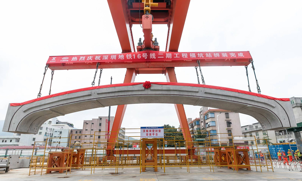 據(jù)介紹，福坑站處于巖溶發(fā)育區(qū)，最大一處溶洞體積近4000立方米，地質(zhì)條件差，對(duì)拼裝時(shí)的圍護(hù)結(jié)構(gòu)變形控制帶來了巨大的挑戰(zhàn)。該項(xiàng)目大力推進(jìn)“智能化+信息化+數(shù)字化”智能制造平臺(tái)建設(shè)，通過BIM模型可視化系統(tǒng)等技術(shù)應(yīng)用，實(shí)現(xiàn)了集勘察、測(cè)量、施工、注漿等于一體的全方位智能化管理。項(xiàng)目組還自主研發(fā)了具備旋轉(zhuǎn)、防搖擺、姿態(tài)微調(diào)、糾偏等多功能“180噸門式起重機(jī)+分離式拼裝臺(tái)車”工裝設(shè)備，實(shí)現(xiàn)了梁、板、柱、墻等預(yù)制構(gòu)件的吊裝、翻轉(zhuǎn)、旋轉(zhuǎn)等姿態(tài)調(diào)整，達(dá)到了毫米級(jí)的精準(zhǔn)拼裝。圖為最后一塊頂板吊裝。