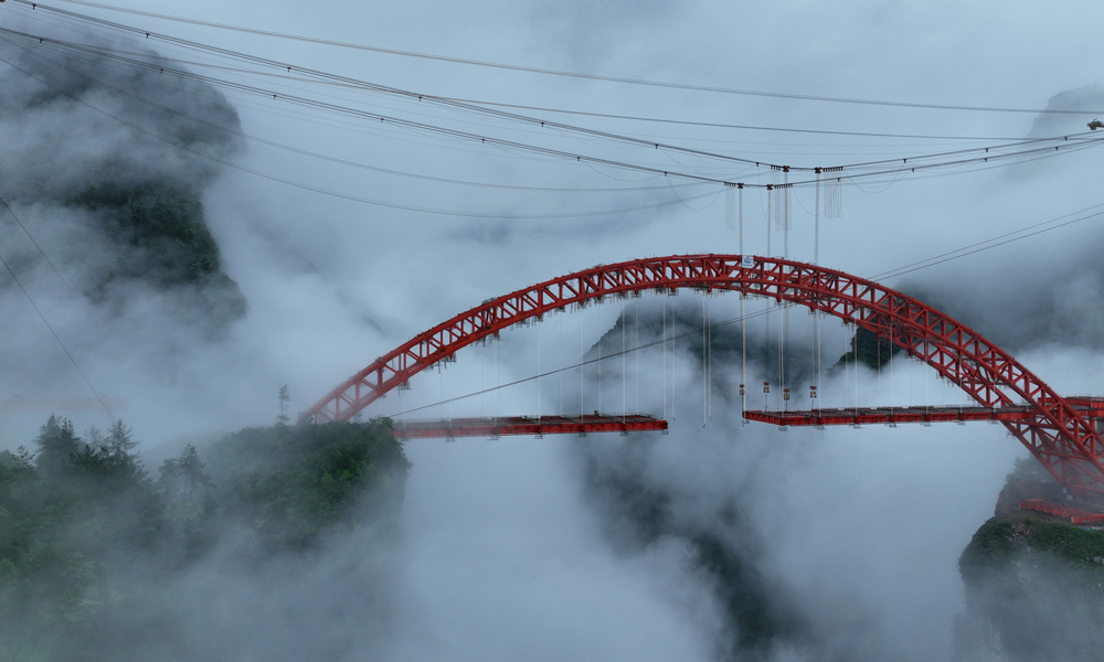 溇水河特大橋主橋為310米主跨的中下承式高低鋼桁拱橋，橋面寬31米，設計為雙向四車道，采用“纜索吊機吊裝+斜拉扣掛法懸臂法”總體方案施工。橋梁拱肋共分為50個節段，最大吊重節段約135噸。目前，大橋鋼拱已拼裝完成，正在進行鋼梁安裝，預計今年7月份完成鋼梁施工，今年年底完成整個大橋的建設。圖為近日拍攝的溇水河特大橋。楊順丕 攝