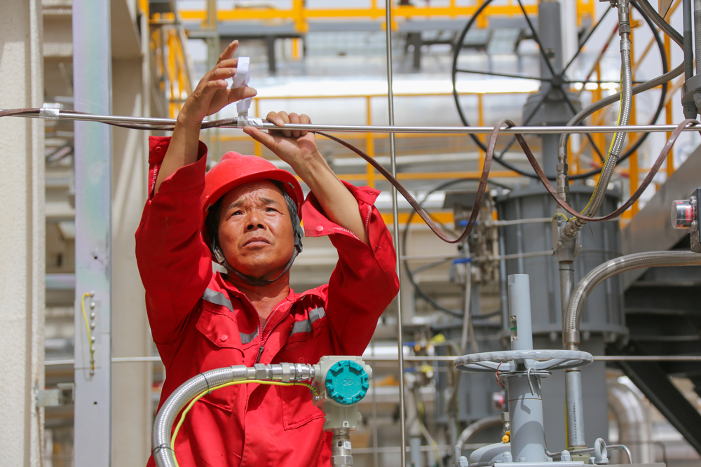 順北油氣田地處塔克拉瑪干沙漠腹地，6月以來該地頻發高溫紅色預警。西北油田采油四廠啟動高溫應急預案，干部員工克服高溫風沙天氣，堅守在上產一線，確保油氣井生產安穩運行。圖為近日，天然氣處理廠維護人員為設備加裝電伴熱。