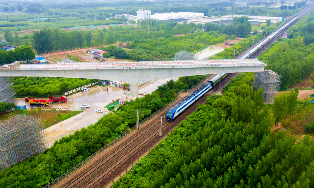 近日，中國中鐵旗下中鐵四局承建的雄安新區(qū)至北京大興國際機場快線跨京九鐵路轉體梁順利合龍，為全線按期通車運營奠定了堅實基礎。圖為跨京九鐵路轉體梁轉體后火車經過轉體橋。