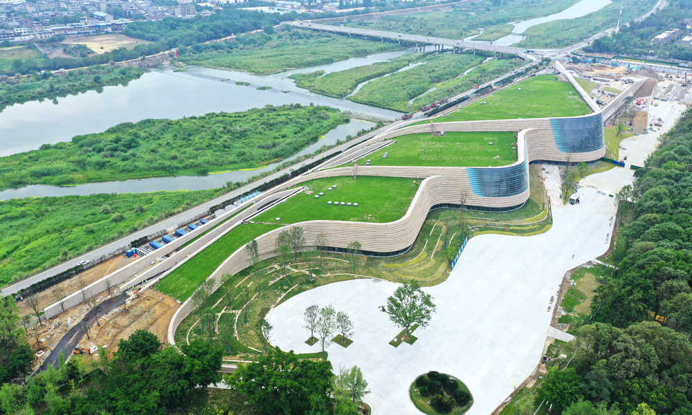三星堆博物館新館屋頂選用了固化纖維土全種植屋面，綠植種植面積約2.7萬平方米。從空中俯瞰，整個新館與大地融為一體，實現(xiàn)了建筑消隱融于環(huán)境的設(shè)計初衷。考慮到斜屋面綠化種植特點，建設(shè)團隊在建設(shè)過程中將植物纖維、有機化合物和營養(yǎng)物質(zhì)通過微波加熱及機械壓縮形成固化土基質(zhì)，用于屋面種植。這種基質(zhì)土層飽水荷載小于45公斤每平方米，可以有效降低屋面覆土荷載，實現(xiàn)了建筑材料從原材料、生產(chǎn)到使用全過程的低碳化，也降低了斜屋面綠植運營養(yǎng)護土壤的營養(yǎng)流失。建設(shè)期間，項目還通過太陽能、風(fēng)能利用，噪音控制、揚塵控制等系統(tǒng)，實現(xiàn)了全過程綠色建造。