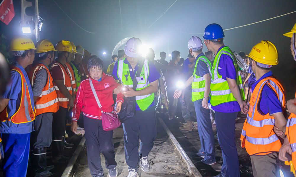 8月2日19時，中鐵十四局京唐項目、北京地鐵17號線項目80余名工作人員兵分兩路，一部分工作人員搬運枕木，重修鐵路路基；另一部分工作人員背靠坍塌部分路基，形成愛心人墻，協助被困Z180列車503名乘客解除困境。侯慧 攝