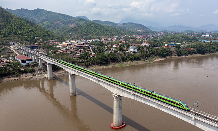 今年恰逢共建“一帶一路”倡議提出十周年。十年來，“一帶一路”倡議合作碩果累累，陸續建成的一系列標志性項目助力各國發展，為各國人民帶來實實在在的好處。從空中俯瞰，這些“國家地標”盡顯恢弘大氣，成為“中國建造”的閃亮名片。中老鐵路北起中國昆明，南抵老撾萬象，全長1035公里，是“一帶一路”共商合作、共建項目、共享紅利的生動例證。截至10月3日，中老鐵路開通運營滿22個月，累計運輸貨物2680多萬噸，其中進出境貨運量550萬噸，貨物品類增加至2700多種。圖為2023年5月28日，中老鐵路客運列車通過老撾瑯勃拉邦湄公河特大橋。新華社發（陳暢?攝）