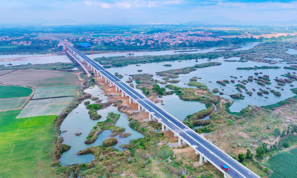 針對(duì)旅游公路建設(shè)點(diǎn)多線(xiàn)長(zhǎng)、作業(yè)面廣、影響因素多等困難，項(xiàng)目團(tuán)隊(duì)充分利用“BIM智慧建造+無(wú)人機(jī)航測(cè)技術(shù)”，將數(shù)字化設(shè)計(jì)和精細(xì)化相結(jié)合，縮短了施工工期，提高了施工質(zhì)量；采用全自動(dòng)滑模機(jī)進(jìn)行混凝土水溝施工，成品外觀平順，強(qiáng)度、結(jié)構(gòu)尺寸等均滿(mǎn)足設(shè)計(jì)要求，降低了施工成本，減少了環(huán)境污染，實(shí)現(xiàn)了智慧建造與綠色工地的高度統(tǒng)一。圖為海南環(huán)島旅游公路昌化江大橋。