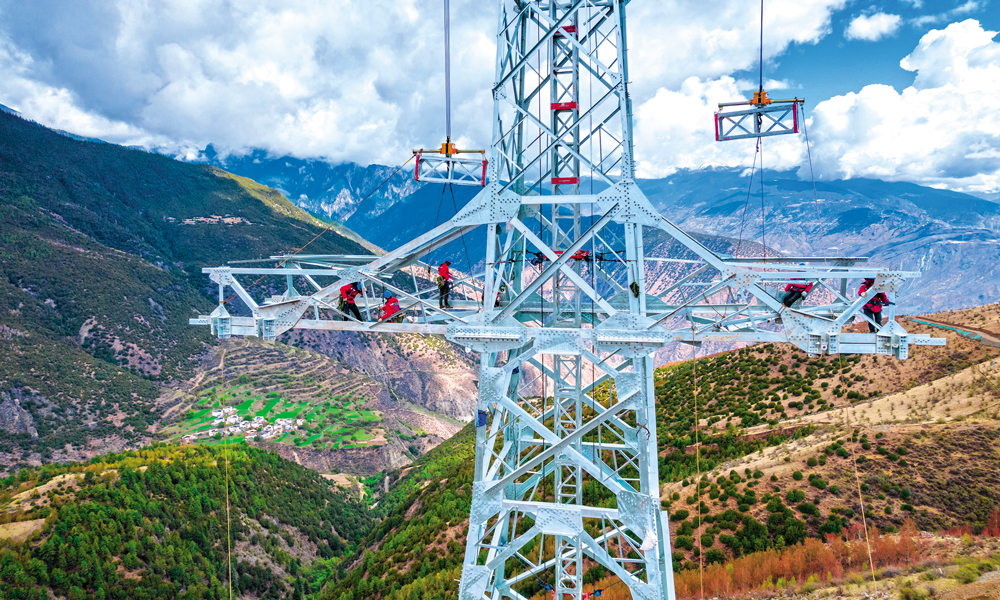 “西電東送”大動脈為經濟社會發展夯基，“沙戈荒”大型風電光伏基地外送工程為產業發展聚力，農村電網持續鞏固提升為改善農牧民生活托底……國家電網有限公司積極服務新時代西部大開發，加快推動電網轉型發展，為進一步形成大保護、大開放、高質量發展新格局作出國網貢獻。圖為國家電網西藏電力施工人員在±800千伏金上—湖北特高壓直流輸電工程線路工程（藏1標）開展組塔作業。