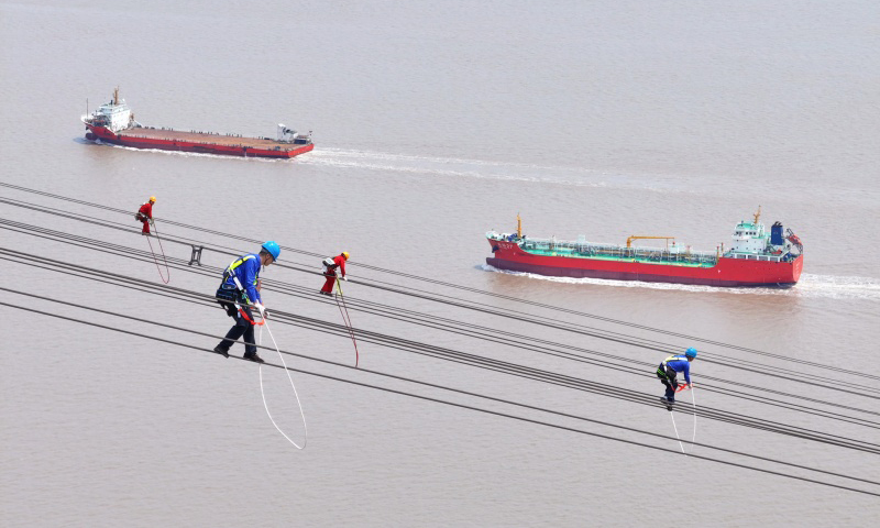 國家電網檢修人員在跨海輸電導線上開展高空走線作業。