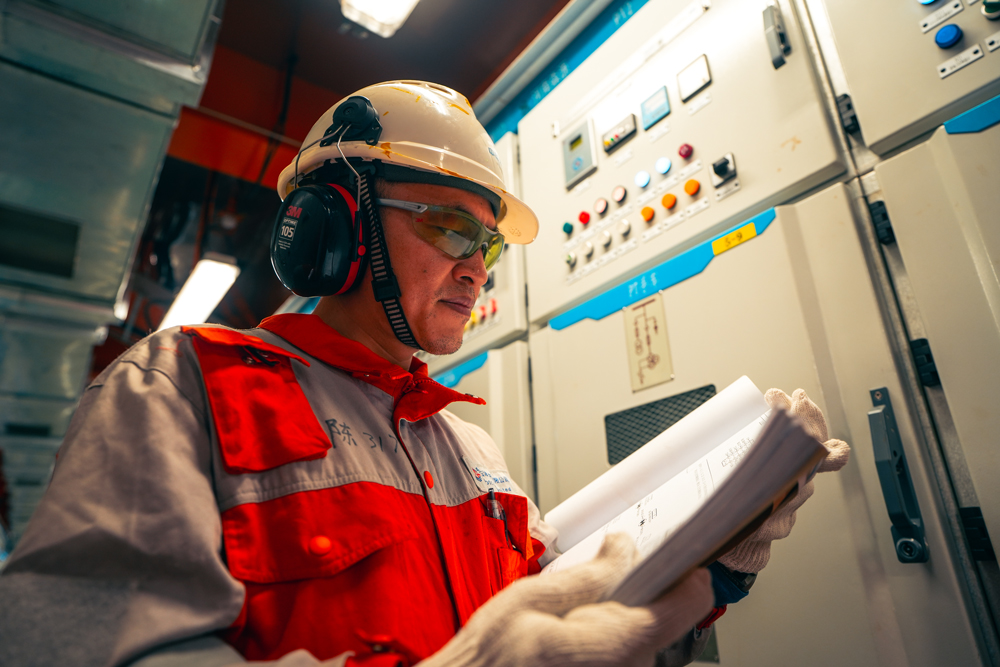 曹妃甸作業公司建立油井經濟效益模型，按照效益分類管理油井，同時加強多專業聯動，開展增儲挖潛工作，立足平臺內“挖”外“擴”，實現所有油田主力平臺加掛井槽，三年內新增槽口90余個，開發新井超140口。圖為海上平臺電氣工程師對照圖紙進行故障排查工作。