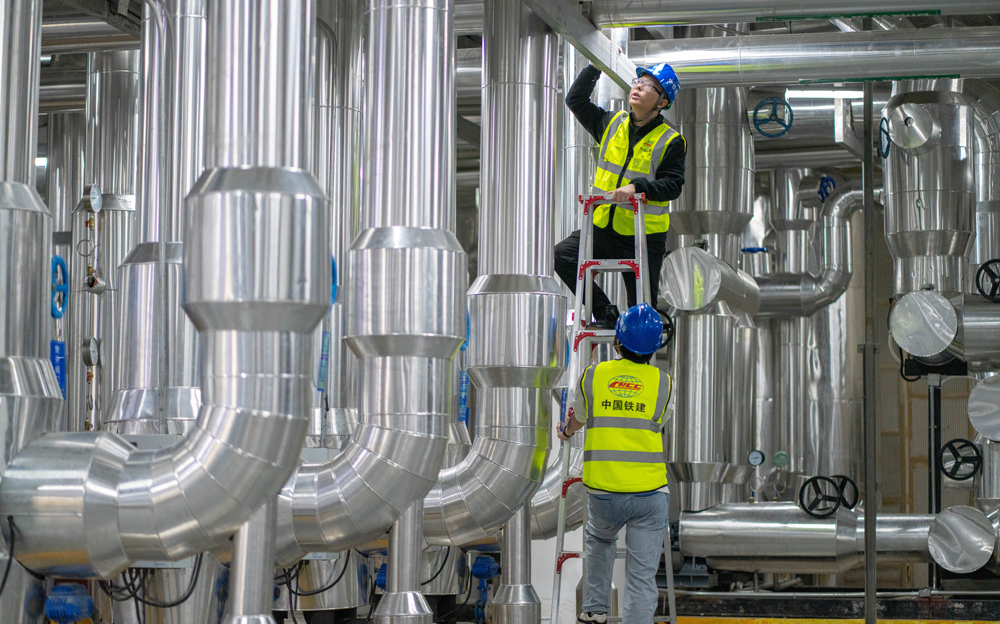 通過博鰲近零碳示范區(qū)運行管理中心，可以實現(xiàn)整個零碳示范區(qū)碳監(jiān)測、碳核算及智慧化運維。中心搭載了智慧能源管控平臺，該平臺運用“CIM+BIM”建設(shè)3D數(shù)字孿生東嶼島模型，接入樓宇管控、燈光照明、環(huán)境監(jiān)測等系統(tǒng)，可視化監(jiān)測管控，定期反饋設(shè)備運行狀態(tài)，根據(jù)建筑空間人數(shù)及室外光照強度，動態(tài)調(diào)節(jié)空調(diào)及燈光。圖為中鐵建設(shè)運維工程師檢查制冷機房設(shè)備運行狀態(tài)。