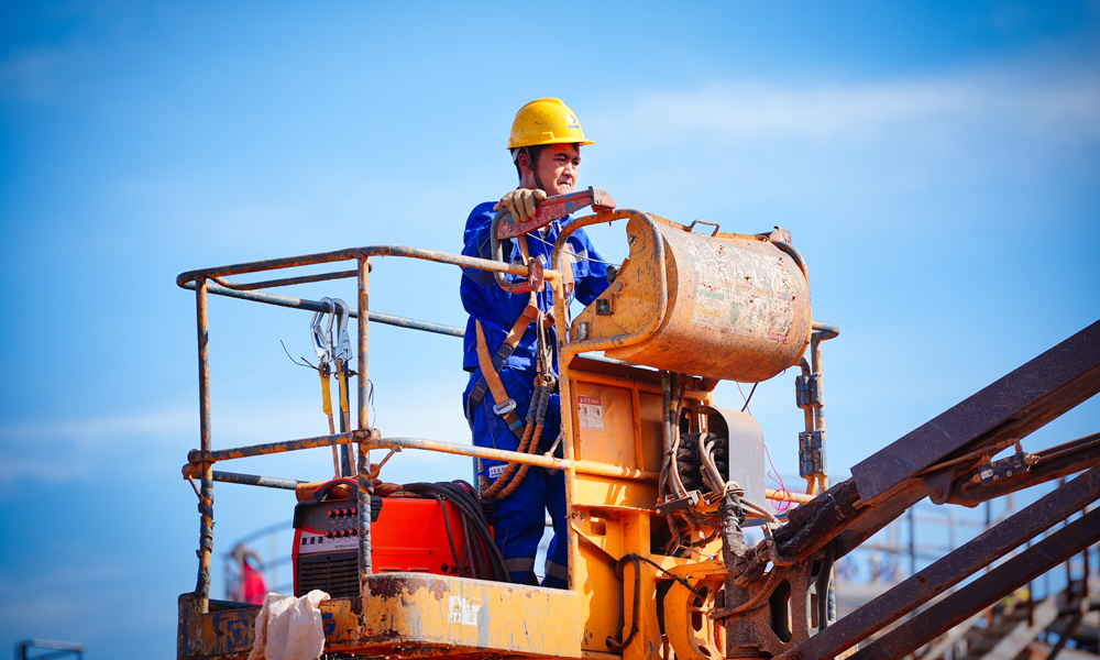 在陸地，建設人員倒排工期快施工，實現了原油處理站、生產水處理站、天然氣液化站、石油氣液化站、變電站、5G基站“六站合一”。其中，生產水處理站采用四級工藝處理生產水，處理后純凈度高。變電站將綠色岸電變壓后輸至海上平臺，替代傳統的燃氣發電，減碳效果突出。5G網絡“連通”海上，為無人機巡檢海上設施、海面24小時溢油苗頭監測等各種智能應用鋪筑了“信息傳輸高速路”。圖為施工人員準備登高作業。