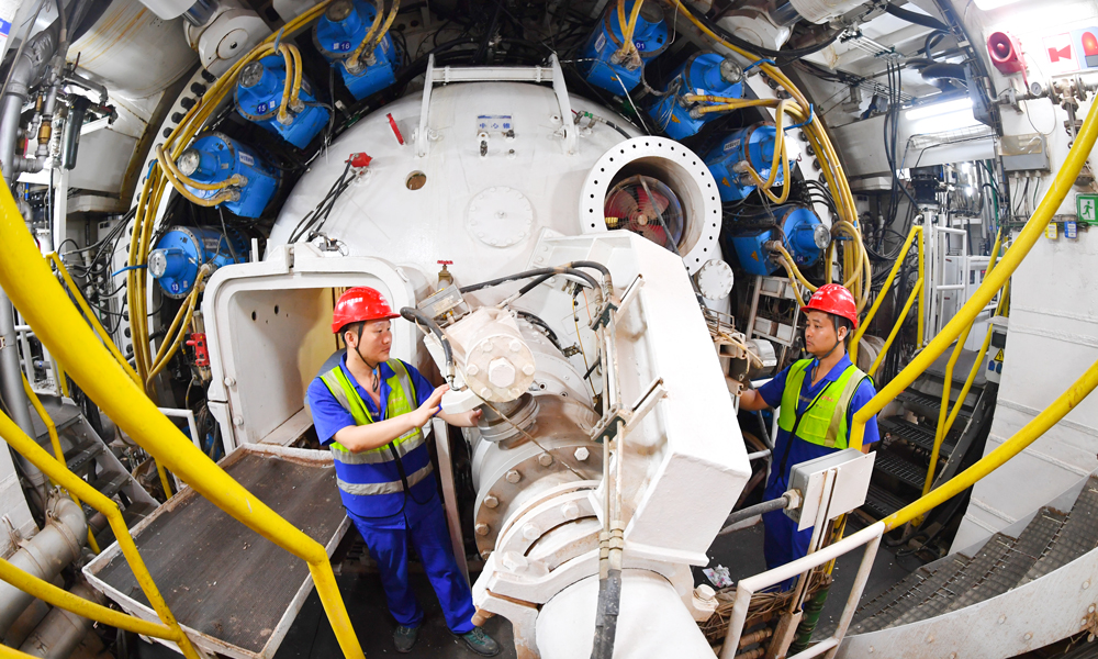 據介紹，隧道最大埋深53米，連續穿越密集建構筑物和珠江多個水道，地質條件復雜，周邊交通繁忙，施工難度大、管理要求高。項目團隊在盾構機進行了針對性設計，配備伸縮式主驅動、伸縮攝像頭、自動測量監控系統、刀具磨損檢測等多項創新技術。施工中采取“原位保護”、樁基托換等，實現了歷史保護建筑毫米級沉降控制，最快月掘進324米，創造我國華南地區復合地層超大直徑泥水盾構掘進紀錄。圖為技術人員檢查盾構機工作狀態。