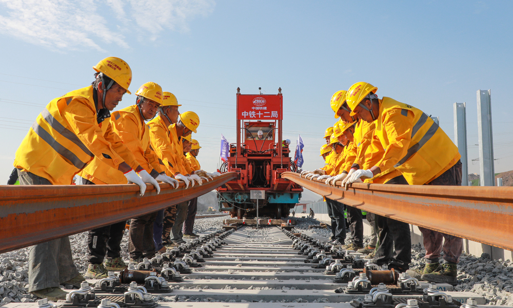 杭溫高鐵建成運(yùn)營(yíng)后，杭州、金華、臺(tái)州、溫州等地的仙華山、仙居、楠溪江等豐富的旅游資源將串聯(lián)成線，沿線仙居、磐安、東陽(yáng)、浦江等地將正式邁入高鐵時(shí)代，對(duì)于推進(jìn)鐵路基礎(chǔ)設(shè)施聯(lián)網(wǎng)、補(bǔ)網(wǎng)、強(qiáng)鏈，打造“軌道上的長(zhǎng)三角”，構(gòu)建浙江省“1小時(shí)交通圈”，便利沿線人民群眾出行，促進(jìn)旅游資源開(kāi)發(fā)和產(chǎn)業(yè)發(fā)展，助力浙江高質(zhì)量發(fā)展建設(shè)共同富裕示范區(qū)和長(zhǎng)三角一體化高質(zhì)量發(fā)展等具有重要意義。圖為鋪軌機(jī)作業(yè)施工現(xiàn)場(chǎng)。