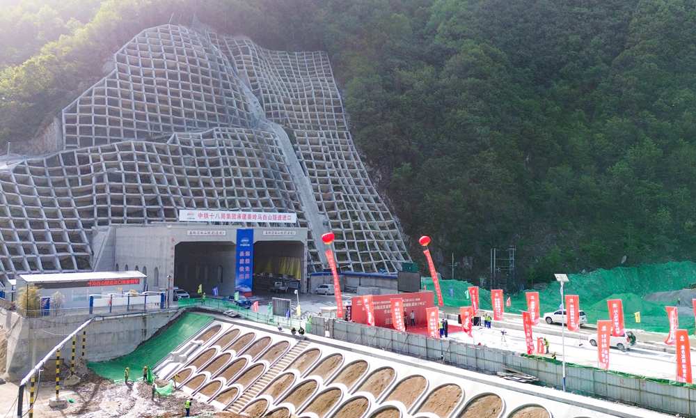西十高鐵秦嶺馬白山隧道位于陜西省西安市藍(lán)田縣境內(nèi)，全長(zhǎng)22.9公里，為雙洞單線隧道，是西十高鐵全線最長(zhǎng)隧道，也是穿越秦嶺山區(qū)的最長(zhǎng)高鐵隧道。該隧道橫穿秦嶺嶺脊，洞身穿越斷層破碎帶2處，最大埋深超過620米，地質(zhì)構(gòu)造復(fù)雜多變，具有巖爆風(fēng)險(xiǎn)高、地質(zhì)條件差異大等特點(diǎn)，施工技術(shù)難度和工程風(fēng)險(xiǎn)極高，是全線的關(guān)鍵性控制工程。圖為隧道入口。 