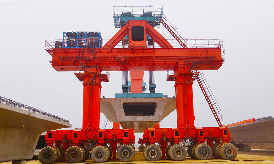 目前，漢壽制梁場(chǎng)已全面實(shí)現(xiàn)復(fù)工復(fù)產(chǎn)，未來將完成785孔箱梁預(yù)制任務(wù)。圖為漢壽制梁場(chǎng)全面配置了900噸級(jí)大型提梁機(jī)、運(yùn)輸機(jī)和自動(dòng)化噴淋養(yǎng)護(hù)設(shè)備，實(shí)現(xiàn)了箱梁全機(jī)械化轉(zhuǎn)運(yùn)、保養(yǎng)維護(hù)。（靳林柱 攝）